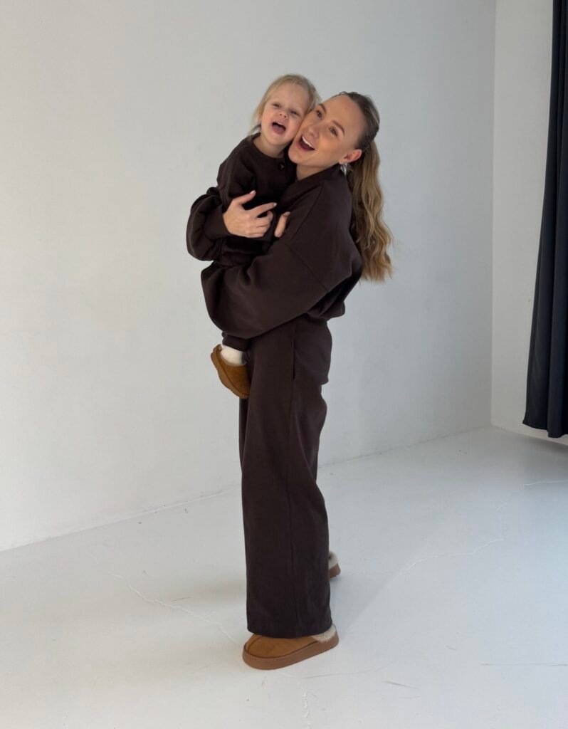 Moteris su vaiku ir rudais džemperių ir kelnių deriniais variantas 1